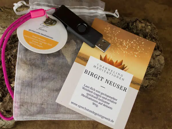 USB Stick schwarz liegt auf einem Organzasäckchen, Meditationsbegleitheftchen mit einem Lotus und Beschriftung Birgit Neuser gechannelte Meditationen liegt dabei